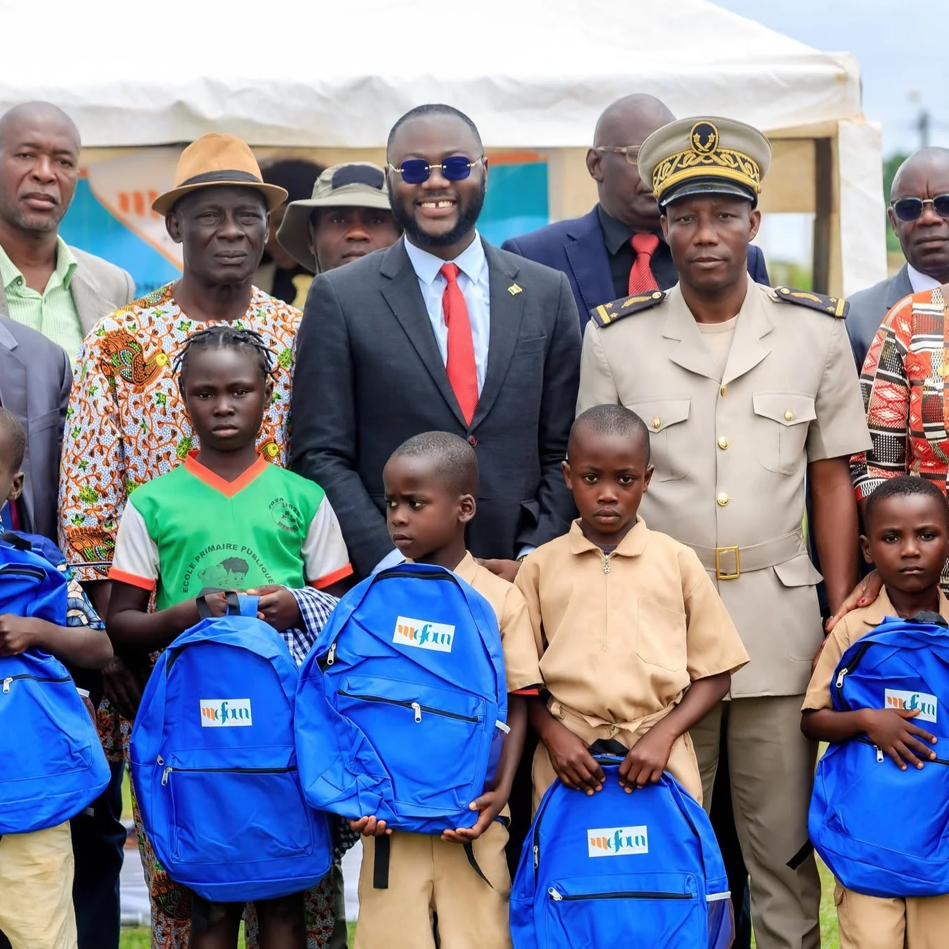 Des enfants avec leurs cartables bleus aux côtés des représentants de MEFOUN et des autorités locales.